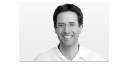 Schwarz-Weiß-Porträt von Dr. Helge Noske in weißem Hemd und Brille, lächelnd vor einem schlichten Hintergrund.