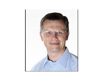 Dr. Wolfgang Zahornitzky in hellblauem Hemd und Brille lächelt vor einem weißen Hintergrund.