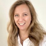 OÄ Dr. Nadja Jiresch lächelnd mit weissem Arztkittel vor beigem Hintergrund